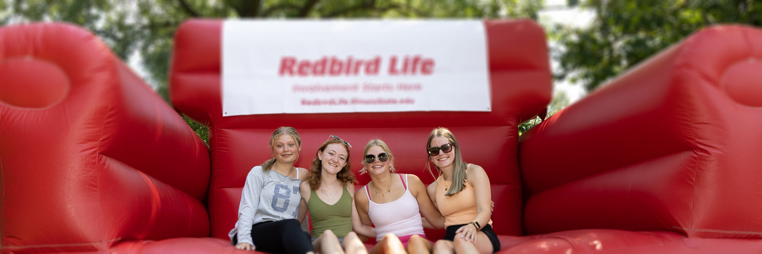 Students posing with Reggie on a big inflatable sofa
